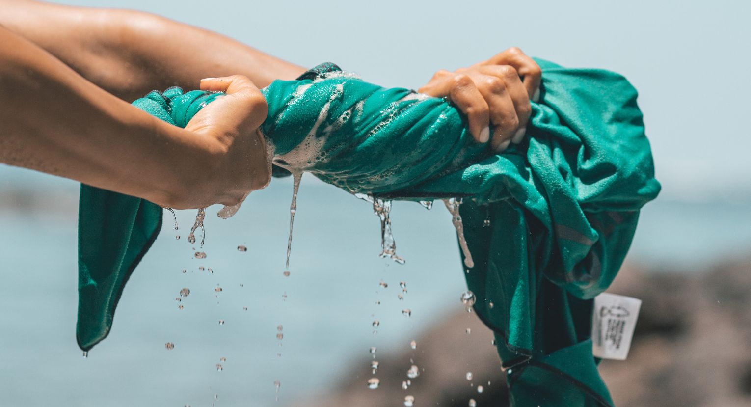 Close-up of hands wringing out a wet Lifeventure towel, showing absorbency and quick drying.